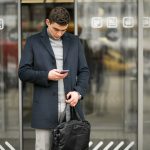 man on an airport entrance with a mobile in his hand