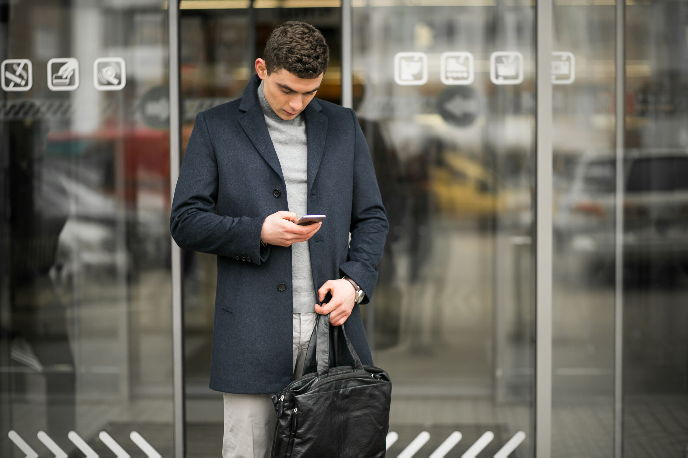 man on an airport entrance with a mobile in his hand