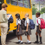 school kids boarding a bus with a female treacher